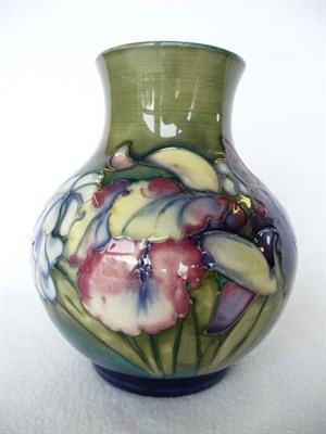 Lot 1725 - A Walter Moorcroft Orchid and Spring Flowers Pattern Vase, circa 1950, on a green/blue ground, blue