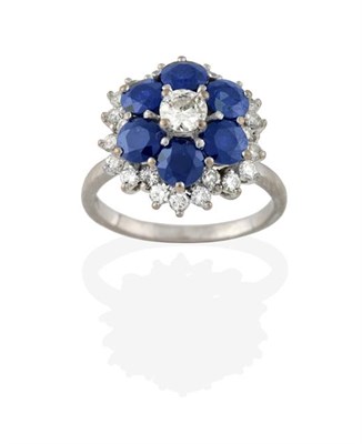 Lot 2285 - A Sapphire and Diamond Cluster Ring, the central raised round brilliant cut diamond in a border...