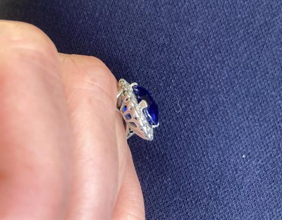 Lot 2296 - A Sapphire and Diamond Cluster Ring, the oval mixed cut sapphire in a white claw setting,...