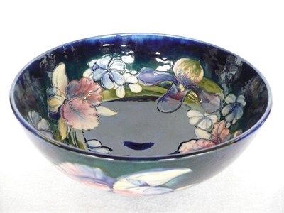 Lot 1727 - A Walter Moorcroft Orchid and Spring Flowers Pattern Bowl, circa 1950, on a blue ground,...