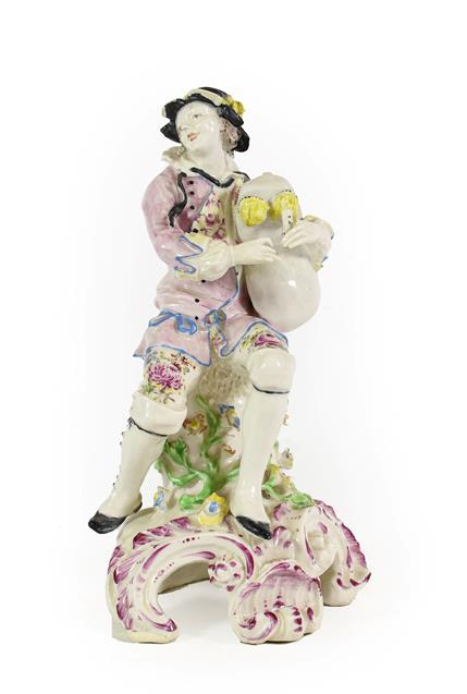 Lot 35 - A Bow Porcelain Figure of a Bagpiper, circa 1765, seated on a rocky outcrop on a scroll moulded...