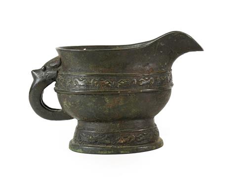 Lot 177 - A Chinese Bronze Ewer, in Archaistic style, of oval form with mask and loop handle and with foliate
