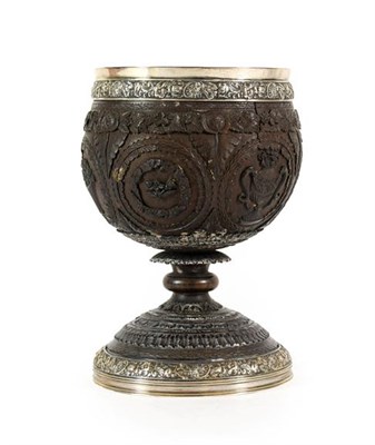 Lot 257 - A George IV Silver Mounted Coconut Cup, the silver London 1822, of ovoid form, carved with...
