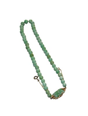 Lot 174 - A graduated jade bead necklace, knotted to a pierced jade plaque stamped '9CT', length 48.5cm