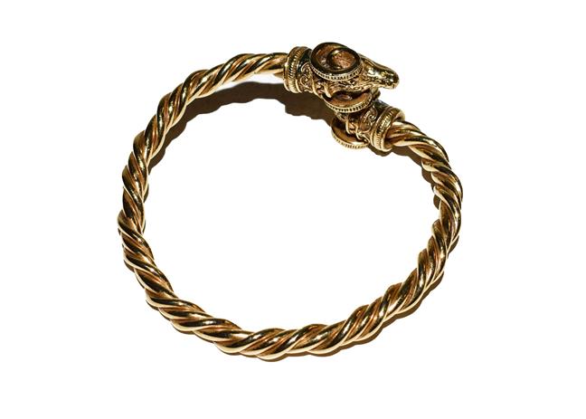 Lot 184 - A yellow metal bangle with rams head terminals
