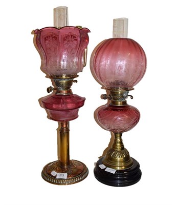 Lot 219 - An Art Nouveau brass based oil lamp with cranberry glass font and etched shade, together with...