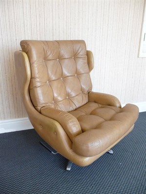 Lot 1873 - A 1970's Tan Leather Swivel Wingback Armchair, with studded seat and back, on an aluminium...