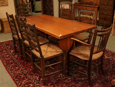 Lot 1152 - A pine kitchen table, together with a set of six rush seated ladder back dining chairs, a rush...