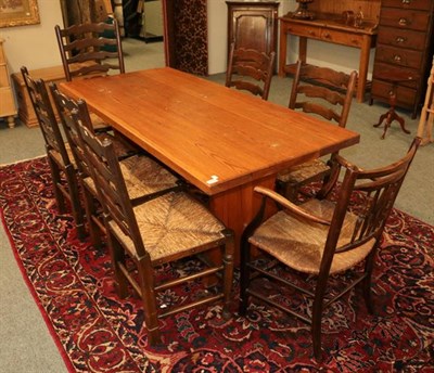 Lot 1152 - A pine kitchen table, together with a set of six rush seated ladder back dining chairs, a rush...