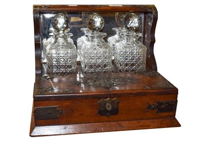 Lot 357 - An early 20th century oak three bottle tantalus with silver plated mounts, and a Bramah lock,...