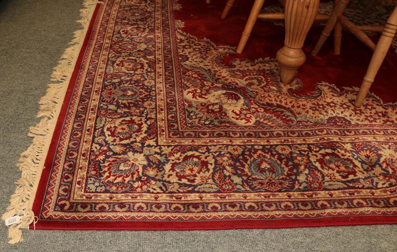 Lot 1076 - Machine made carpet of oriental design, the blood red field with central medallion framed by...