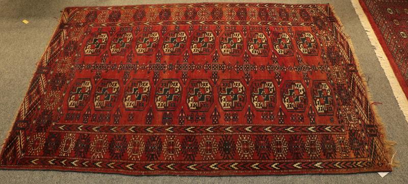 Lot 1077 - Paskistani Bukhara rug, the deep terracotta field with four columns of guls enclosed by stellar...