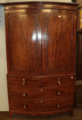 Lot 1098 - A Regency mahogany bow-front linen press, raised over a three-height chest base over splay...