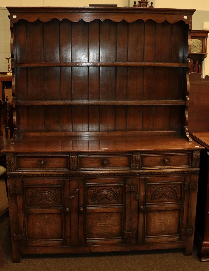 Lot 1181 - A 20th century carved oak dresser and rack with three drawers over cupboards, 137cm by 43cm by...