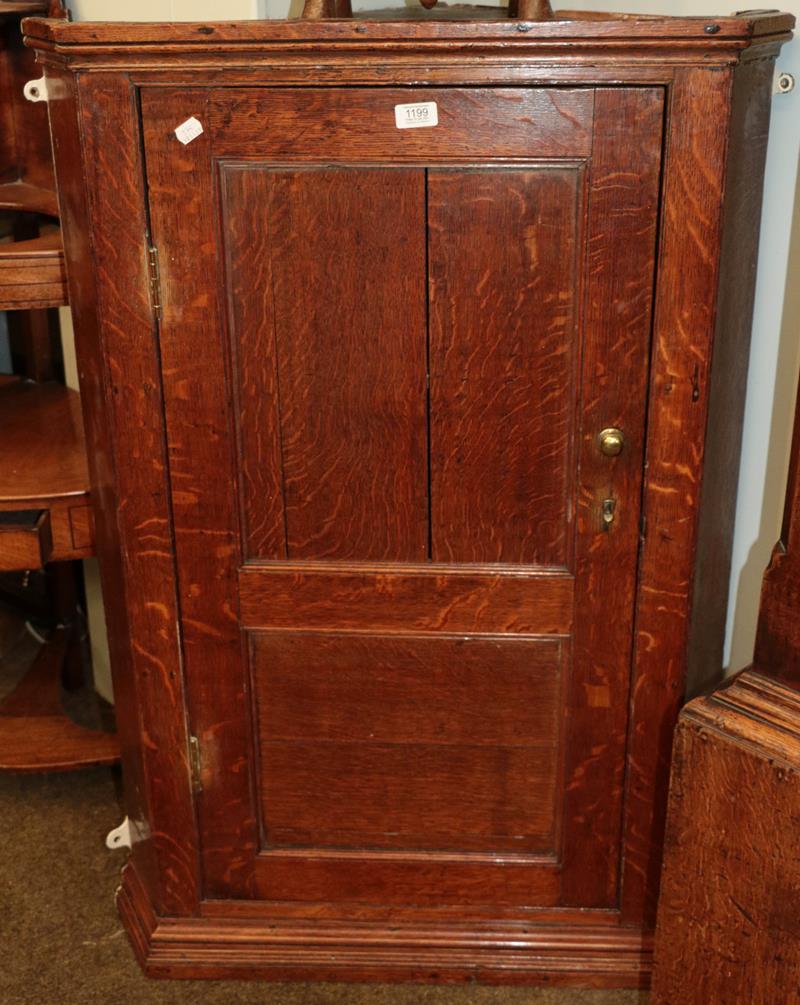 Lot 1199 - A George III oak hanging corner cupboard with panelled door, 75cm by 46cm by 110cm