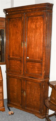Lot 1257 - A large Georgian oak standing corner cupboard, with panelled doors and fluted pillasters, 114cm...