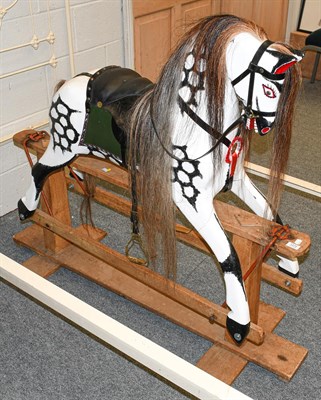Lot 1272 - A painted dappled rocking horse on trestle base, 130cm by 114cm high to the tip of the ears