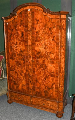 Lot 1314 - A 20th century Dutch marquetry inlaid walnut armoire with carved arch top and two-drawer base...