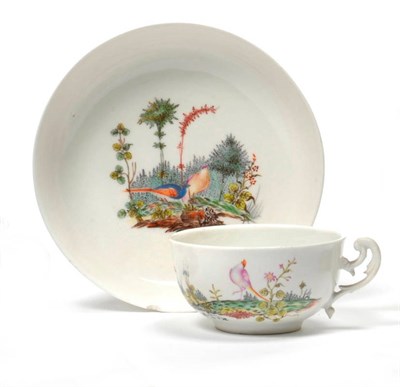 Lot 160 - A Nymphenburg Porcelain Teacup and Saucer, circa 1765, with scroll handle, painted by Josef...
