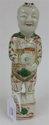Lot 209 - A Chinese Porcelain Figure of a Boy, Kangxi, standing holding a vase, painted in famille verte...