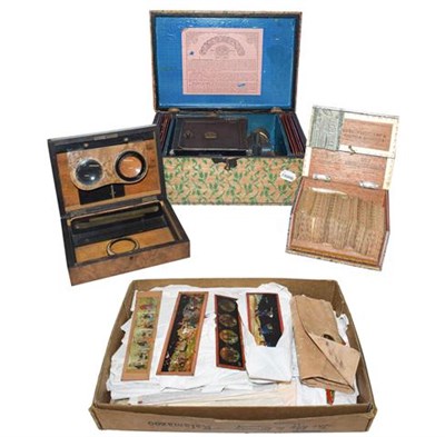 Lot 427 - ~ A boxed German magic lantern marked E. P., a box of glass cartoon slides, a walnut cased...