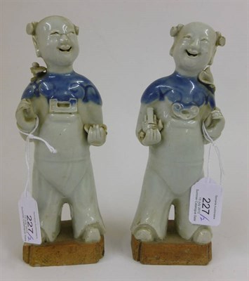 Lot 227 - A Pair of Chinese Porcelain Figures of Boys, 18th century, each standing holding an object,...