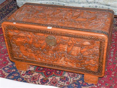 Lot 1095 - ~ A 20th century oriental carved camphor wood trunk, decorated to in relief with boating...