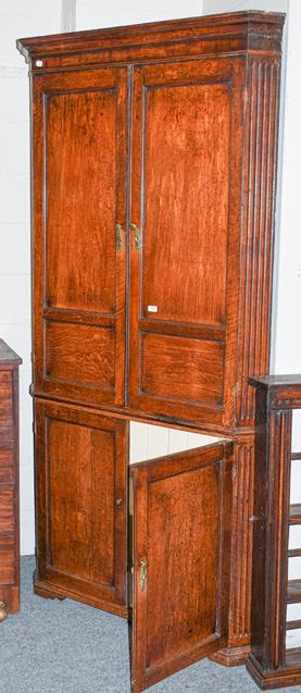 Lot 1103 - A large Georgian oak standing corner cupboard, with panelled doors and fluted pilasters, 114cm...
