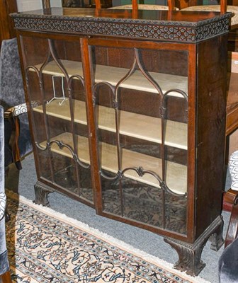 Lot 1153 - ~A mahogany astragal glazed bookcase with blind fret carving and raised on ogee bracket feet, 123cm