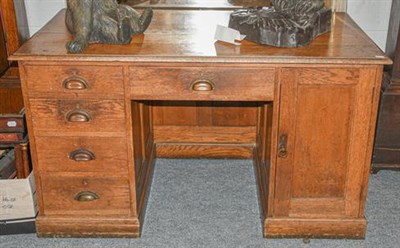 Lot 1165 - An oak pedestal desk with a set of four drawers and a cupboard