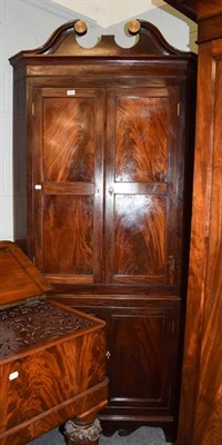Lot 1284 - A George III mahogany standing corner cupboard with swan neck pediments, panelled doors and...