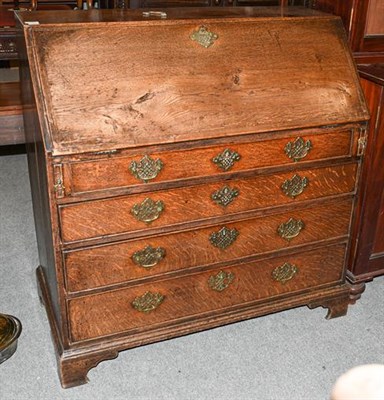 Lot 1302 - A George III oak bureau with fitted interior raised on a four-height chest base on bracket...