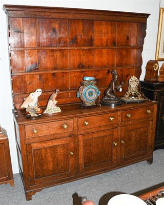 Lot 1378 - A George III oak dresser and rack with brass handles, panelled doors and bracket feet 180cm by 52cm