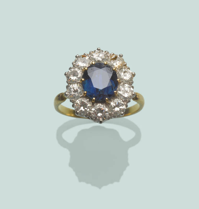 Lot 592 - A Mid 20th Century Sapphire and Diamond Cluster Ring, the oval mixed cut sapphire in a border...