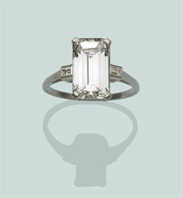 Lot 772 - A Baguette Cut Diamond Solitaire Ring, the step cut stone with truncated corners in a white...
