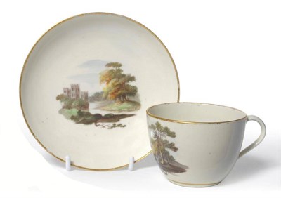 Lot 121 - A Pinxton Porcelain Teacup and Saucer, circa 1800, painted with landscape vignettes within gilt...