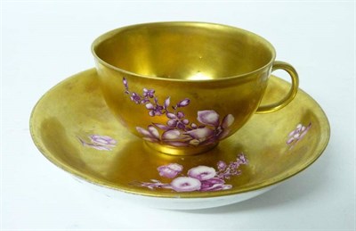 Lot 161 - A Meissen Gold Ground Teacup and Saucer, circa 1750, painted in puce monochrome with flower sprigs