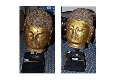Lot 285 - A Pair of South East Asian Gilt Carved Stone Heads, in Archaic style, 26cm high, wooden bases