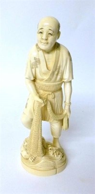 Lot 299 - An Ivory Okimono of a Fisherman, early 20th century, standing in traditional garb holding a...