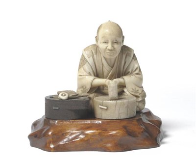 Lot 302 - A Japanese Ivory and Wood Okimono of a Millstone Maker, Meiji period, the seated figure holding...