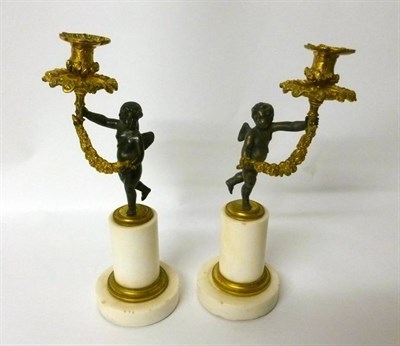 Lot 320 - A Pair of Parcel Gilt Bronze Figural Candlesticks, late 19th century, shaped as a winged putto...