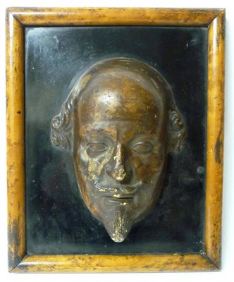 Lot 329 - A Patinated Mask of William Shakespeare, mounted on a polished slate panel in a wooden frame,...