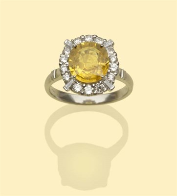 Lot 497 - An 18 Carat White Gold Yellow Sapphire and Diamond Cluster Ring, the oval mixed cut sapphire within