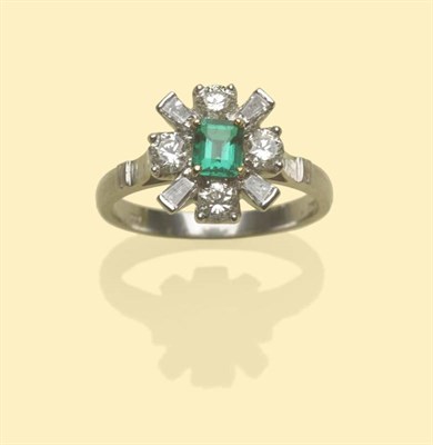 Lot 503 - An 18 Carat White Gold Emerald and Diamond Cluster Ring, the central step cut emerald in yellow...