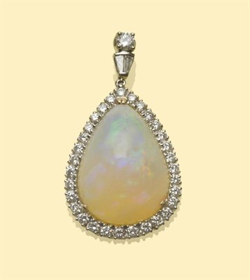 Lot 504 - An 18 Carat White Gold Opal and Diamond Pendant, a triangular domed cabochon opal within a...