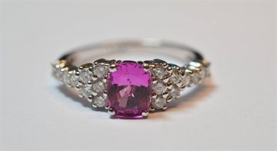 Lot 525 - A Pink Sapphire and Diamond Ring, the cushion cut pink sapphire flanked by tiers of round brilliant