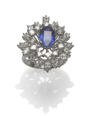 Lot 535 - An 18 Carat White Gold Sapphire and Diamond Cluster Ring, an oval mixed cut sapphire centrally,...