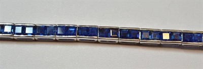 Lot 539 - An 18 Carat White Gold Sapphire Line Bracelet, pairs of square step cut sapphires in broad claw...