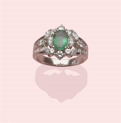 Lot 575 - An Emerald and Diamond Cluster Ring, an oval mixed cut emerald centres a border of round...