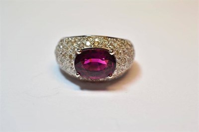 Lot 586 - A Pink/Purple Tourmaline and Diamond Ring, the oval mixed cut tourmaline within a chunky...